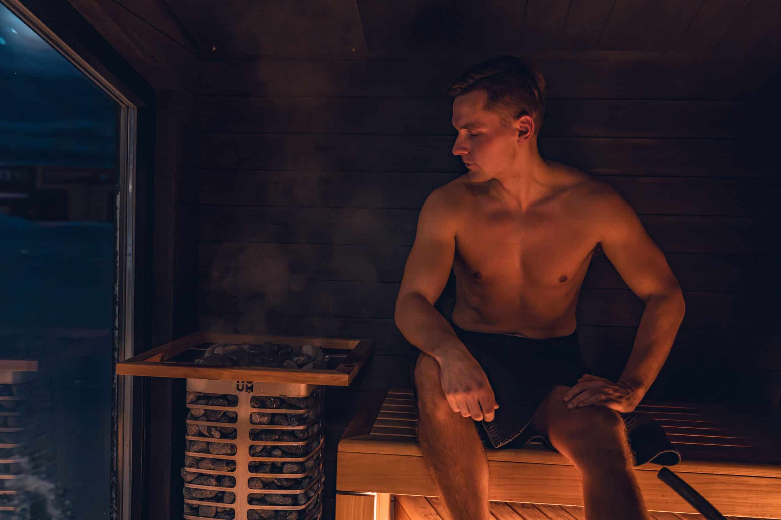 Infrared Sauna For Muscle Recovery: 7 Amazing Ways 1 A person relaxing inside a modern wooden infrared sauna cabin to support post-workout recovery.