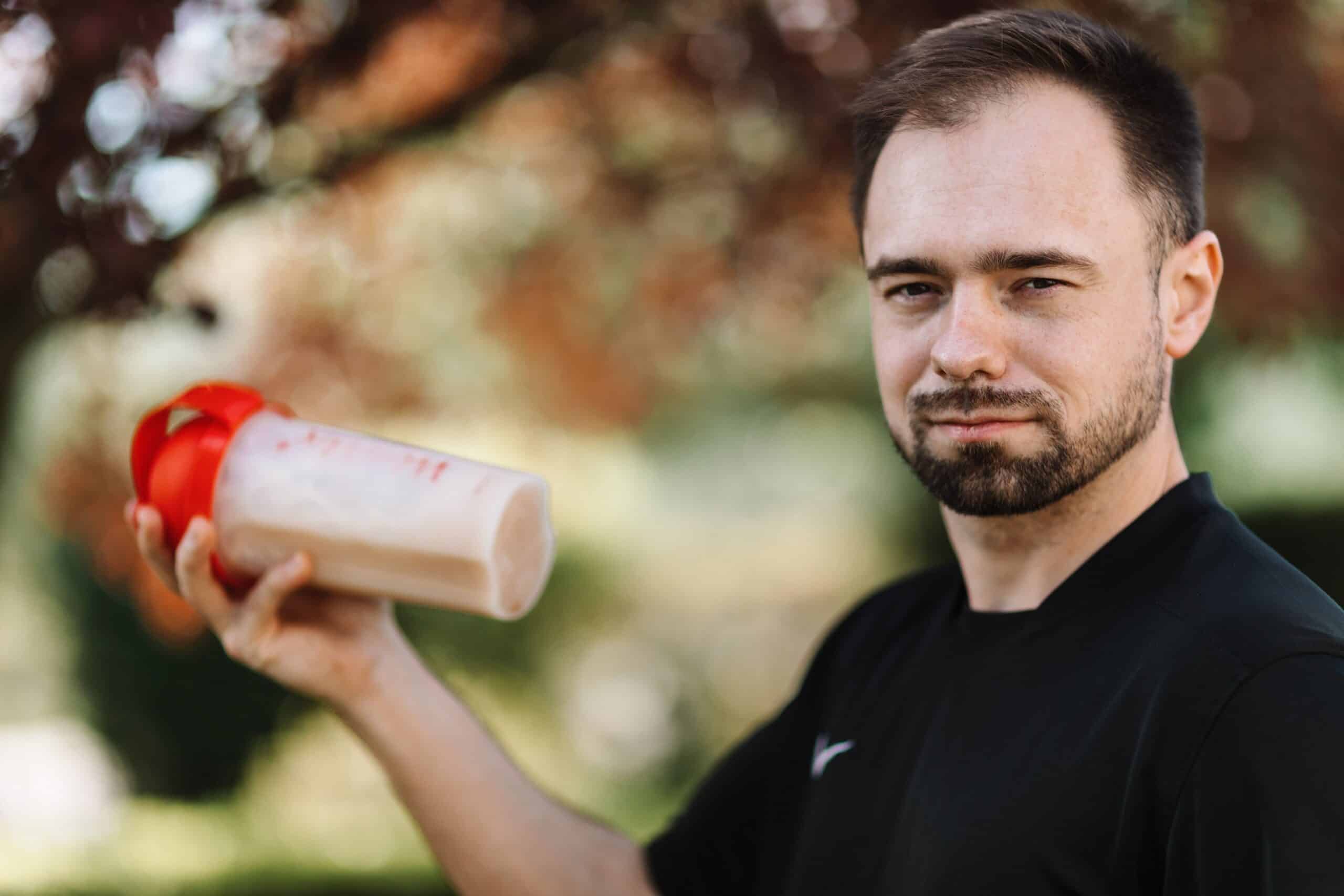 Protein Powder for Muscle Recovery: The Complete Guide 1 A plastic scoop with whey protein powder next to a sports shaker bottle, highlighting protein powder for muscle recovery.