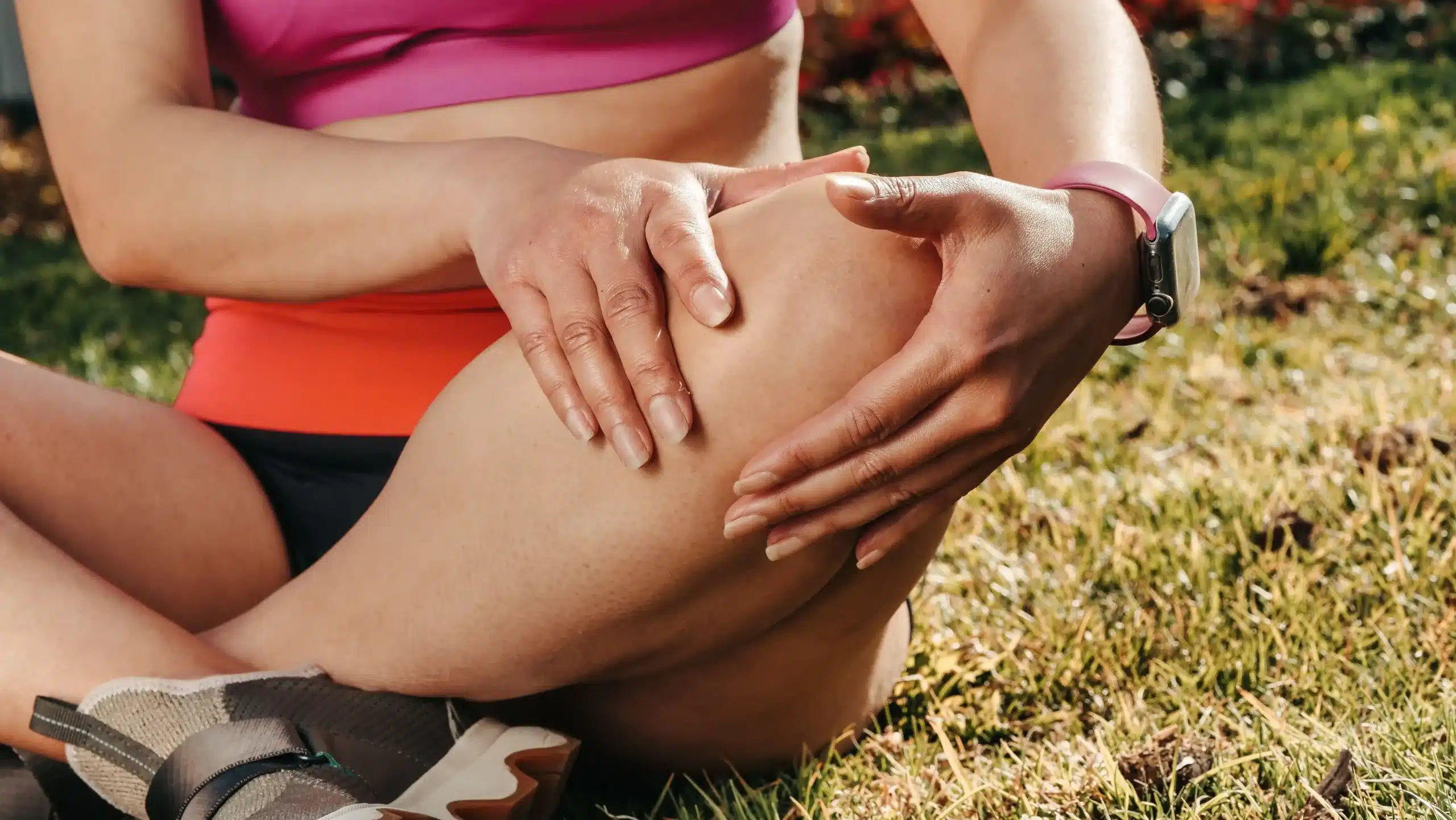 An athlete gently massaging a sore thigh muscle to speed up muscle strain recovery safely.