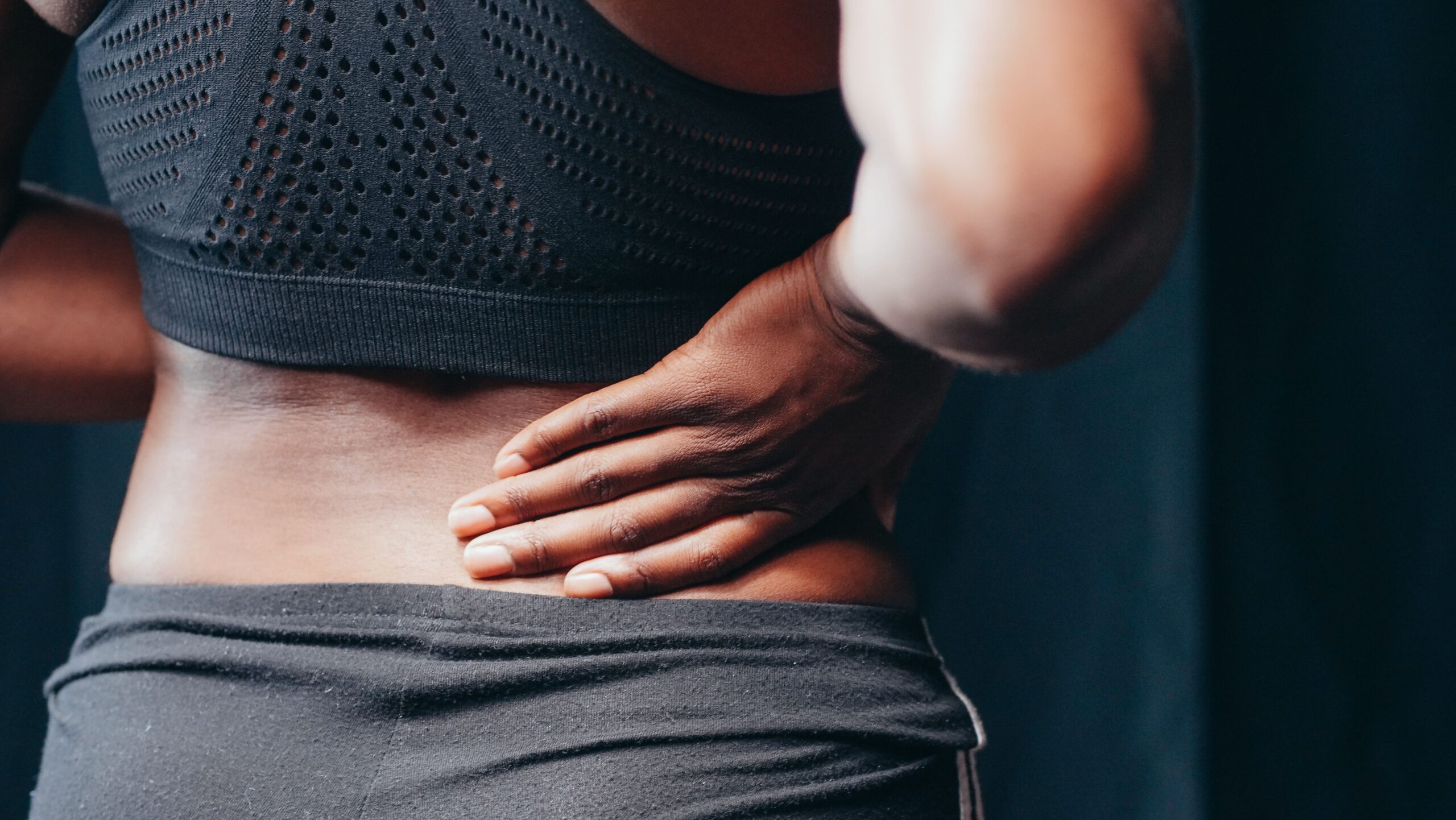 An athlete holding their lumbar spine, illustrating a pulled lower back muscle recovery time timeline.